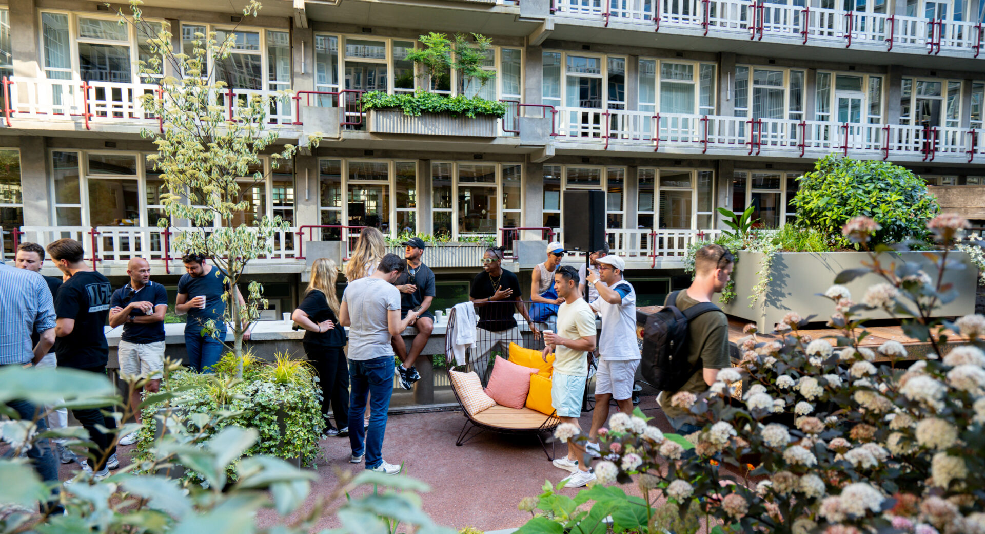 Medewerkers lunchen in de door Blooming Buildings aangelegde kantoortuin vol diverse soorten planten en bloemen.